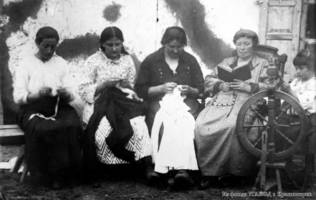 German village/colony residents at leisure - sitting on a bench mending clothes, a woman reading a book, a girl behind a spinning wheel. Approx. 1927-1928.